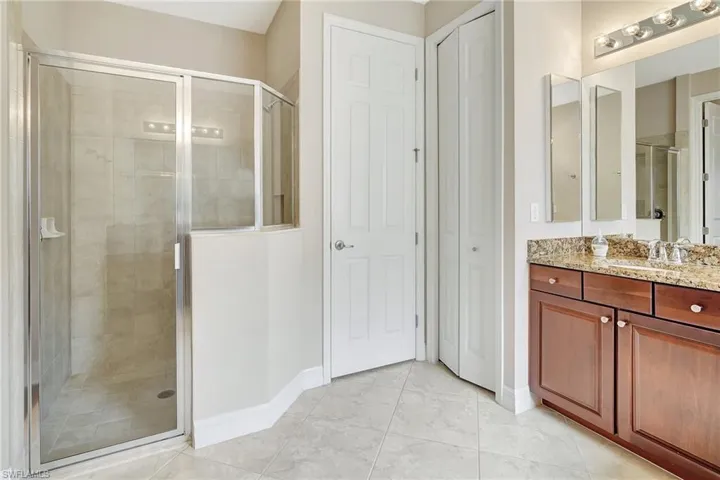 Bathroom featuring vanity, a shower with shower door, and tile patterned flooring