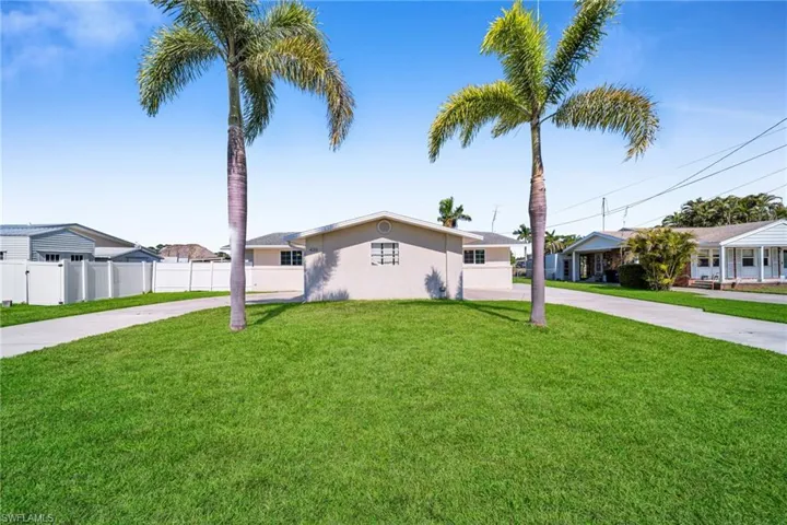 View of front of property with driveway, a front yard, fence, and stucco siding