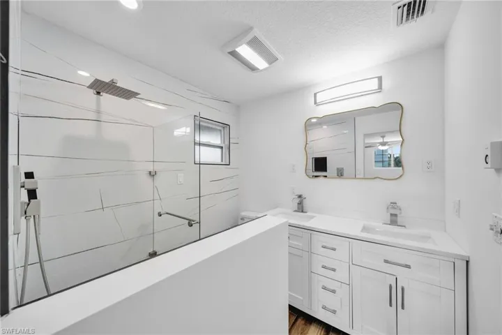 Bathroom with visible vents, a walk in shower, and a sink
