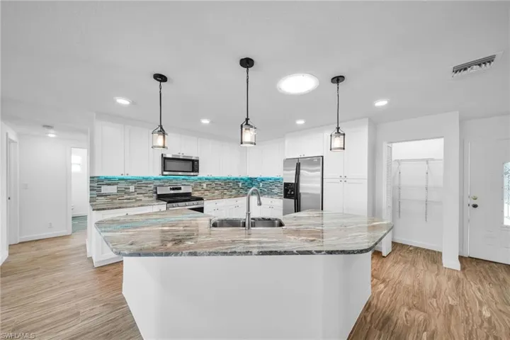 Kitchen with white cabinetry, a sink, stainless steel appliances, and visible vents