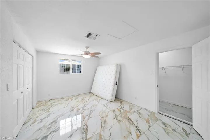 Unfurnished bedroom with marble finish floor, visible vents, a closet, and attic access
