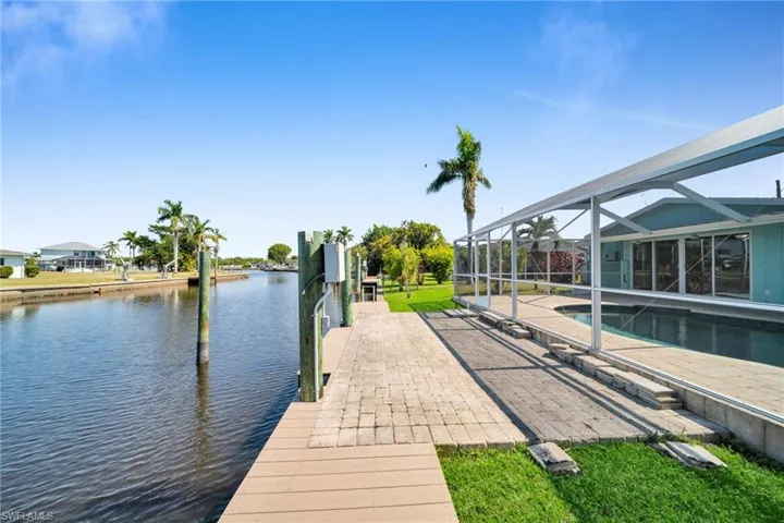 View of dock featuring a patio, a water view, a lanai, and an outdoor pool