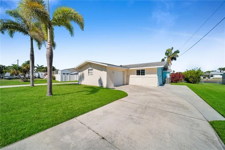 View of front of property featuring concrete driveway, stucco siding, fence, an attached garage, and a front lawn