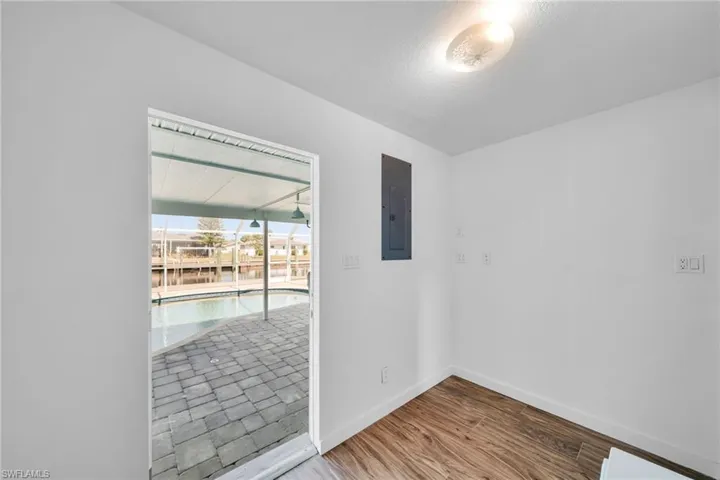 Unfurnished room featuring baseboards, a textured ceiling, wood finished floors, and electric panel