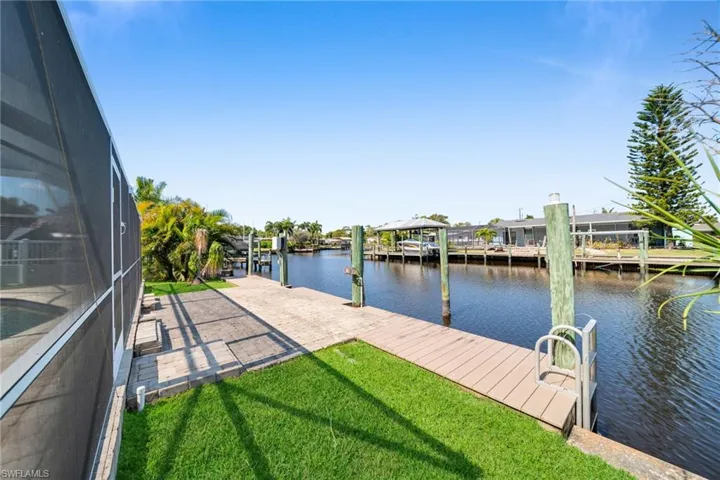 Dock area with a water view, a lanai, and a yard