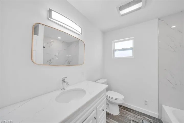 Bathroom with visible vents, baseboards, toilet, wood finished floors, and vanity