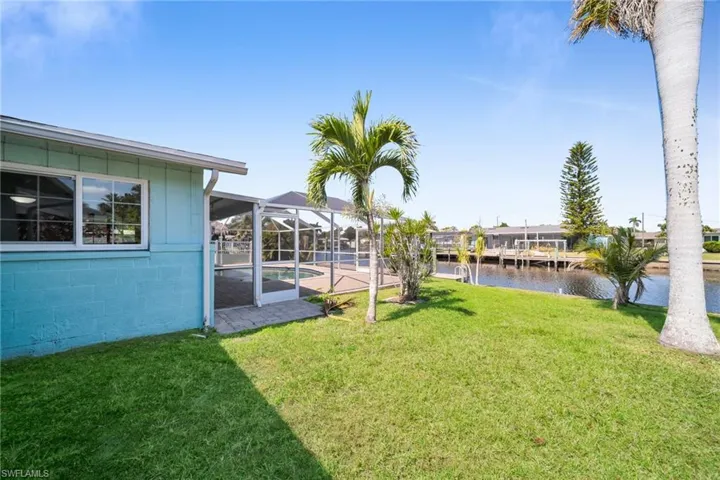 View of yard featuring an outdoor pool, a water view, and glass enclosure