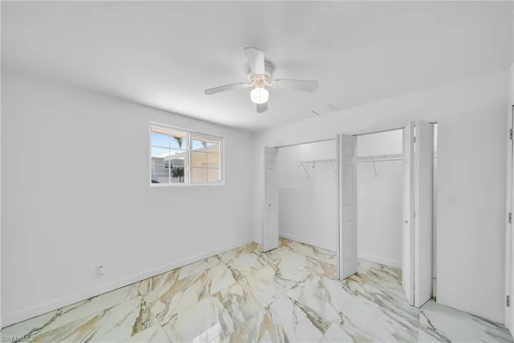 Unfurnished bedroom with baseboards, marble finish floor, ceiling fan, and a closet