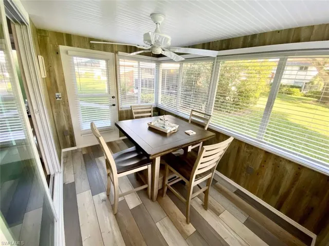 Sunroom featuring outdoor dining area, wood walls, ceiling fan, wood-type flooring, and healthy amount of natural light
