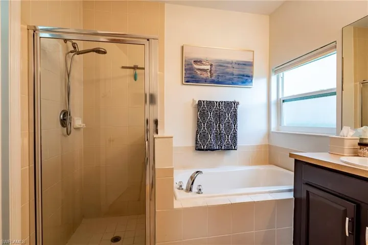 Bathroom featuring vanity, a garden tub, and a stall shower