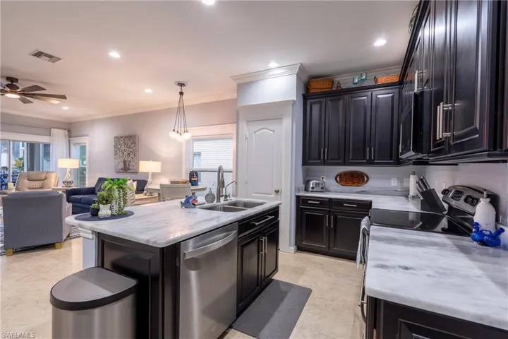 Kitchen featuring open floor plan, stainless steel appliances, crown molding, recessed lighting, and decorative light fixtures