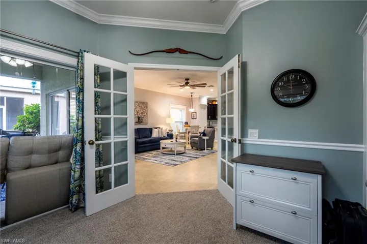 Doorway to outside featuring french doors, ornamental molding, carpet, and ceiling fan