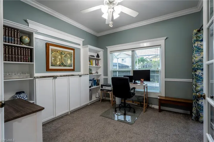 Office space with light carpet, crown molding, and a ceiling fan