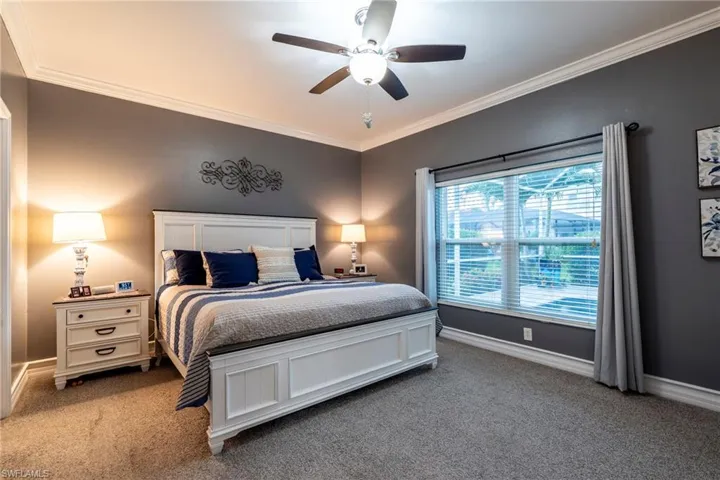 Carpeted bedroom with ornamental molding and a ceiling fan