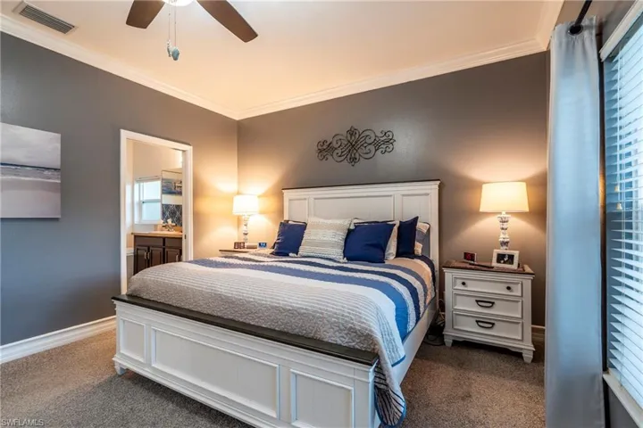 Bedroom featuring ornamental molding, carpet, a ceiling fan, and connected bathroom