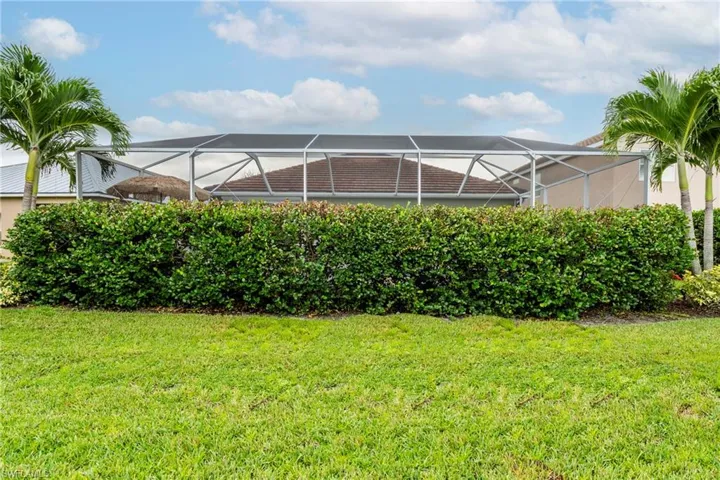View of grassy yard with a sunroom and a lanai