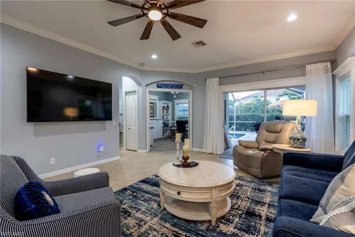 Living area with arched walkways, crown molding, ceiling fan, and recessed lighting