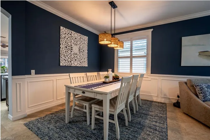 Dining area featuring crown molding, a decorative wall, a wainscoted wall, arched walkways, and ceiling fan