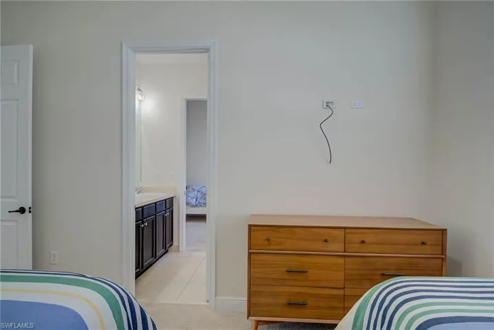 Bedroom with light carpet, ensuite bathroom, and light tile patterned floors