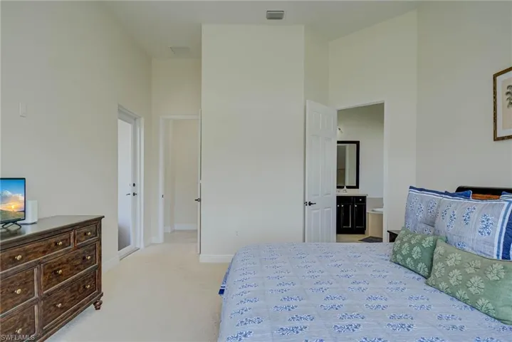 Bedroom with light carpet, connected bathroom, and a towering ceiling