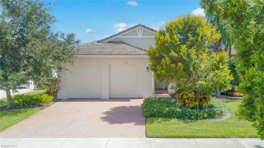 View of front facade with a tiled roof, decorative driveway, stucco siding, and a garage