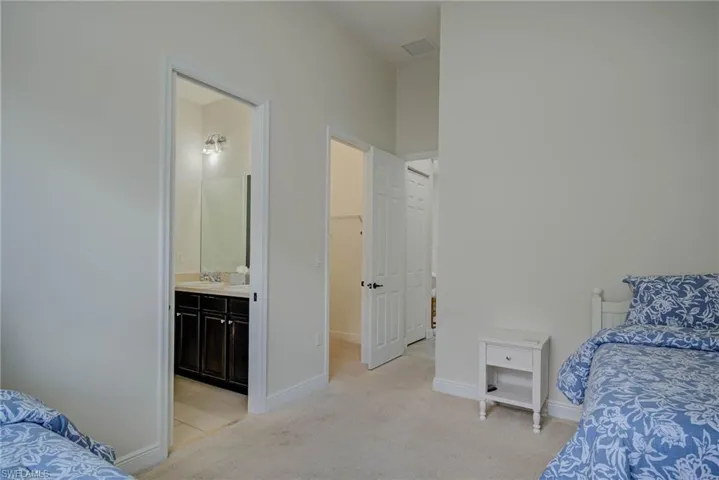 Bedroom with light carpet, a spacious closet, and ensuite bath