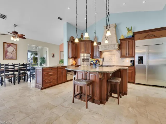 Kitchen featuring kitchen peninsula high vaulted ceiling, pendant lighting, and stainless steel appliances