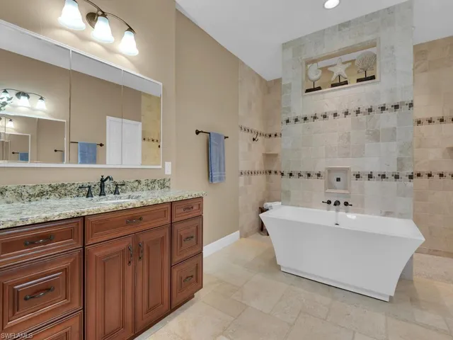 Bathroom with vanity, a tub, and tile walls