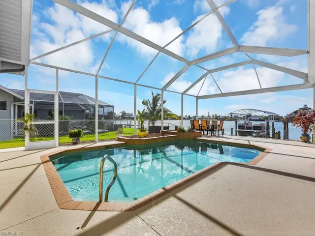 View of pool with a patio, a water view, and glass enclosure