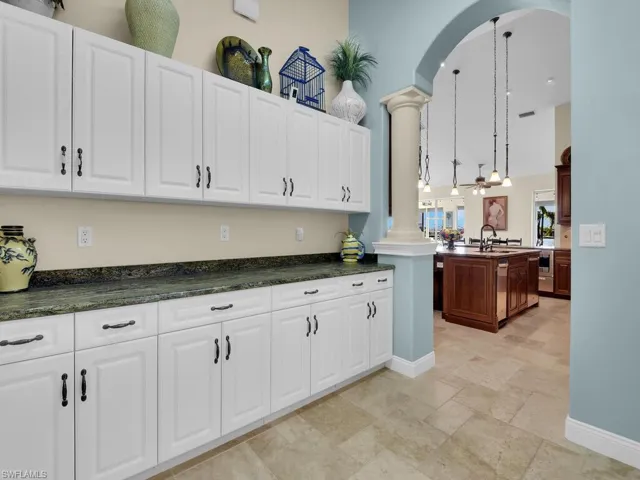 Kitchen featuring white cabinetry, decorative columns, sink, and hanging light fixtures