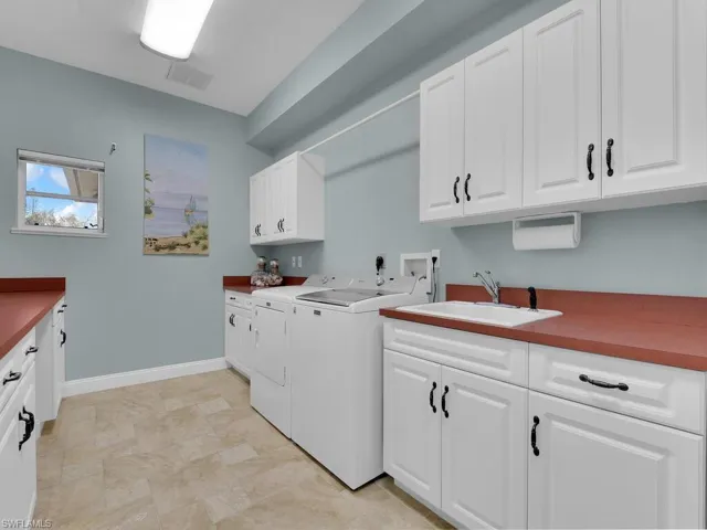 Laundry room featuring cabinets, sink, and washer and clothes dryer