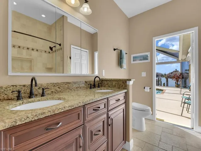 Bathroom featuring vanity, tiled shower, a water view, and toilet