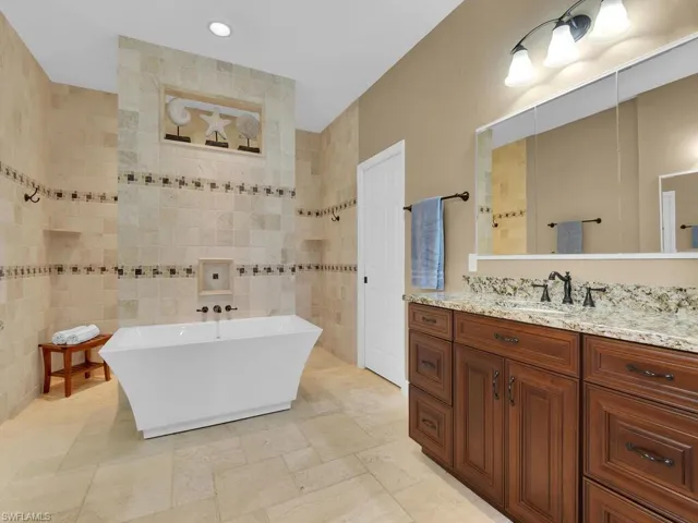 Bathroom with vanity, tile walls, and a bath