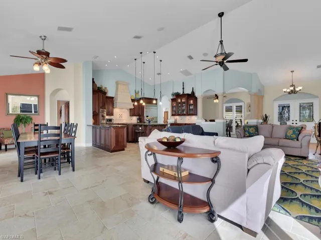 Living room featuring ceiling fan with notable chandelier and high vaulted ceiling