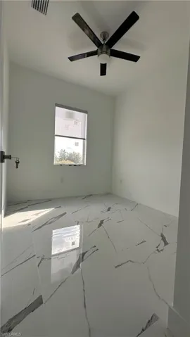 Spare room with a ceiling fan and marble finish floors
