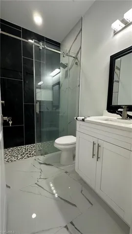 Bathroom featuring vanity, a stall shower, and marble finish floors