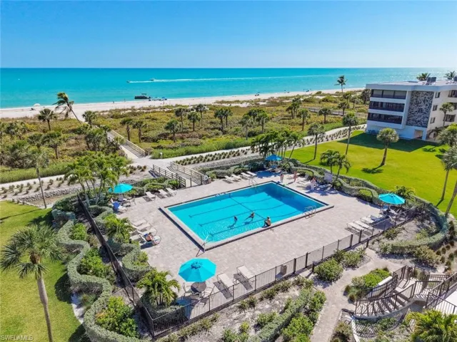 Community pool featuring a patio area and view of water and beach