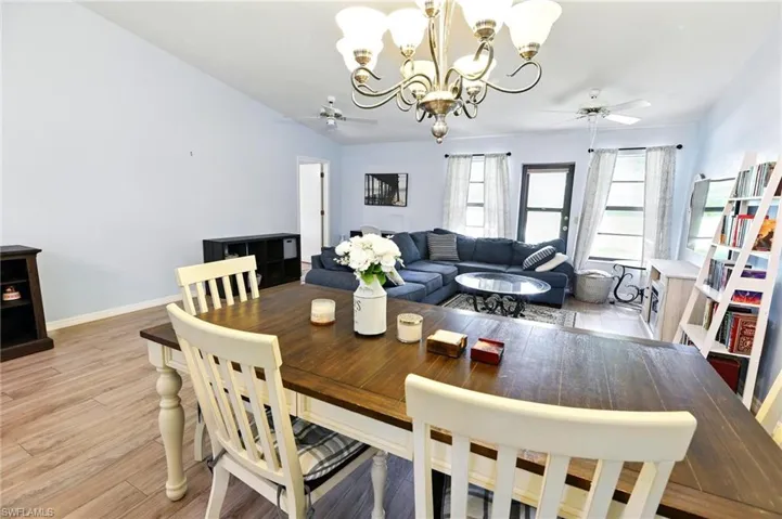 Dining room featuring light wood-style flooring, ceiling fan with notable chandelier, and baseboards