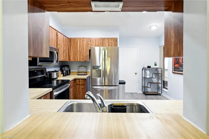 Kitchen featuring a sink, brown cabinetry, stainless steel appliances, light wood-style flooring, and light countertops