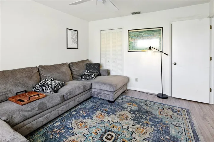 Living area with baseboards, ceiling fan, visible vents, and wood finished floors
