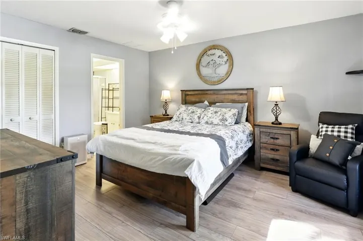 Bedroom with a closet, ensuite bath, visible vents, and light wood-style flooring