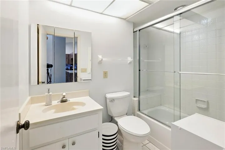 Bathroom with vanity, toilet, and combined bath / shower with glass door