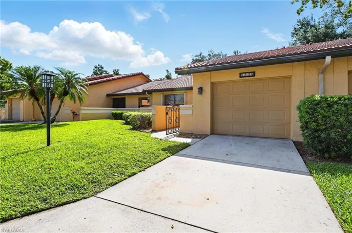 View of front of home featuring a tiled roof, stucco siding, driveway, and a garage