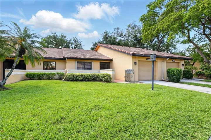 Single story home featuring a tiled roof, stucco siding, driveway, and a front yard