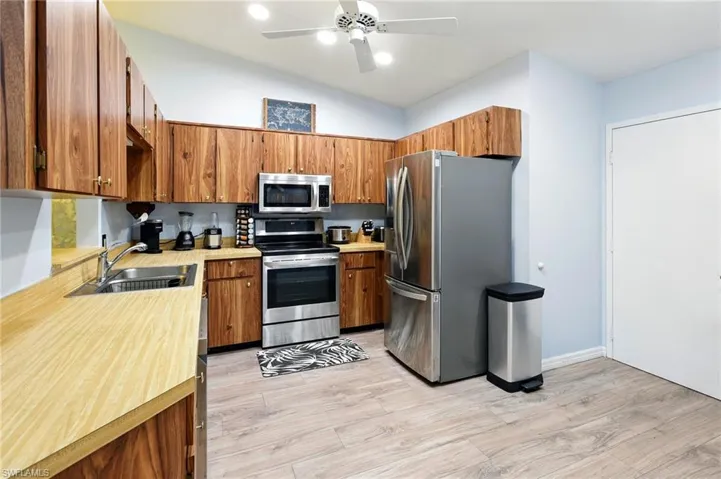 Kitchen with a sink, lofted ceiling, brown cabinetry, light countertops, and appliances with stainless steel finishes