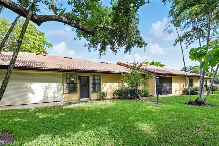 View of the back of the house featuring stucco siding, a tiled roof, and a front lawn