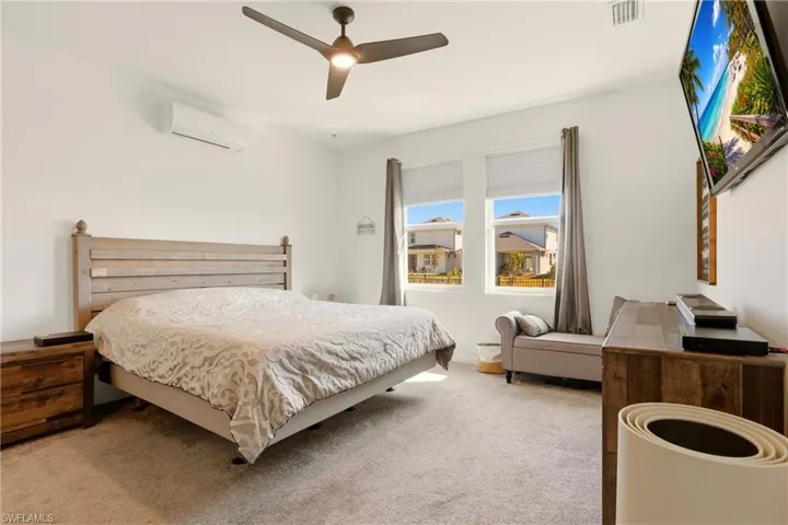 Carpeted bedroom featuring ceiling fan and a mini split for heating / cooling