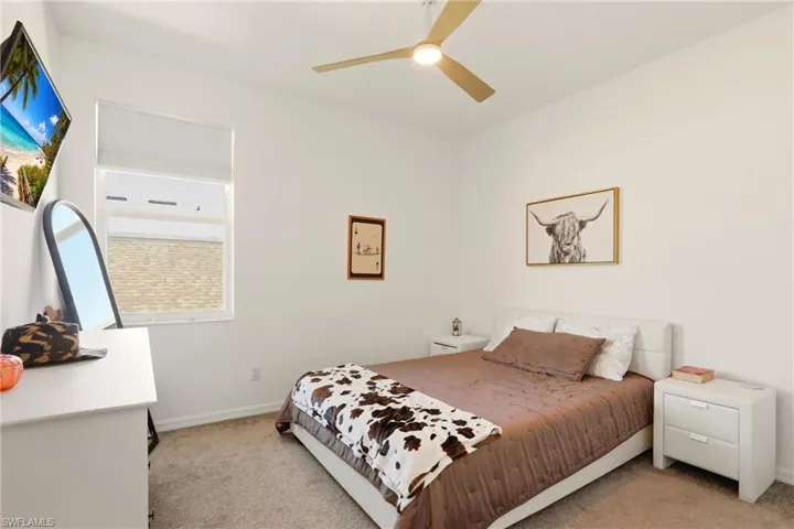 Bedroom with light colored carpet and a ceiling fan