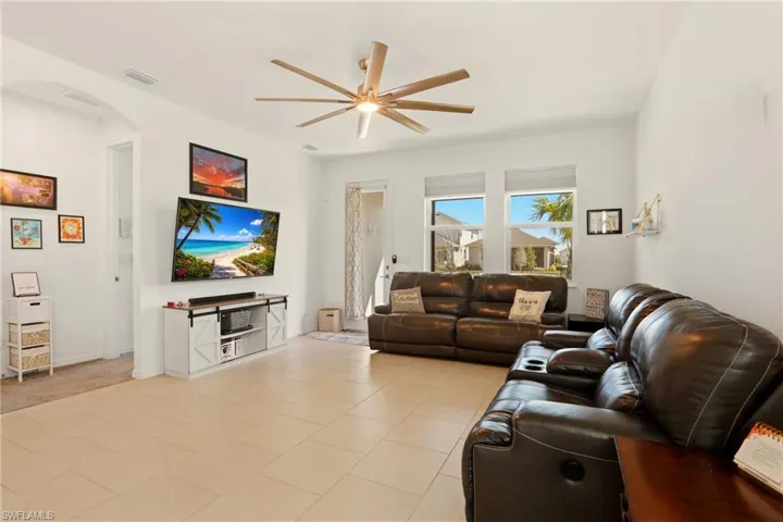 Living room featuring arched walkways, ceiling fan, and light tile patterned flooring