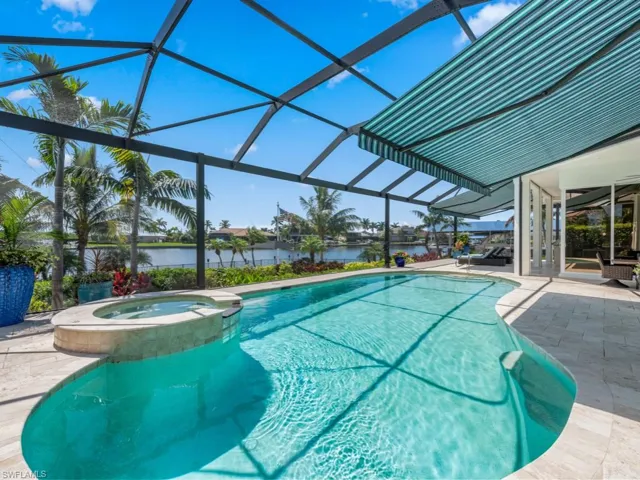 View of swimming pool featuring a patio area, an in ground hot tub, a water view, and a lanai